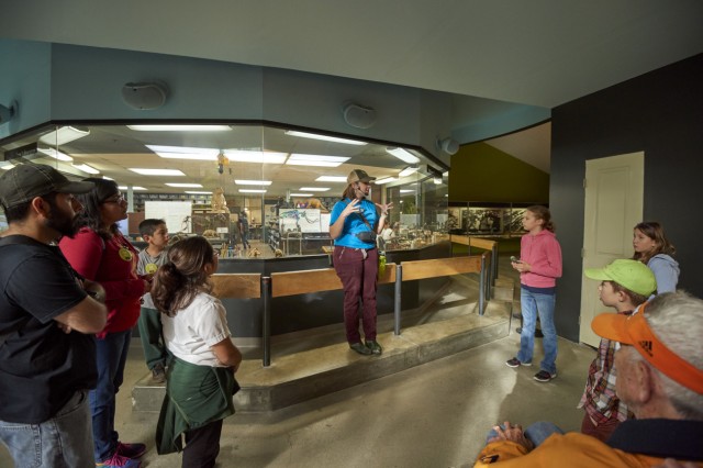 Museum Educator standing outside the Fossil Lab speaking to visitors