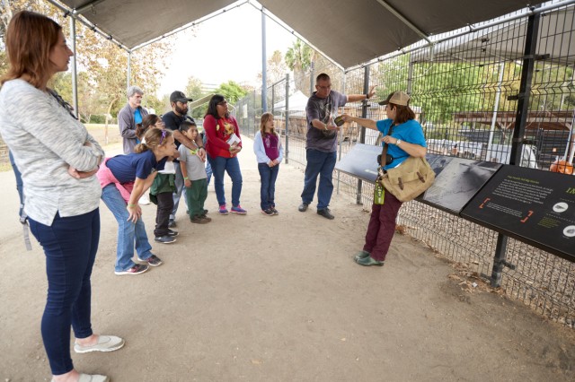 Museum Educator speaking to visitors standing in a semi circle around them