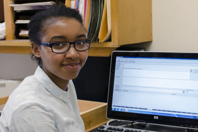 Adriana Stephenson seat at a desk with their hands resting on an open laptop computer