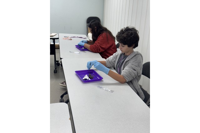 Two students wearing gloves, working with a specimen on a tray