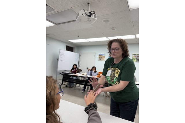 Student touching a snake that Leslie Gordon is holding