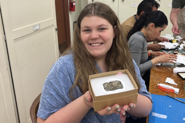Intern Kassi Price holding a specimenn in a box in the Vert Paleo Lab