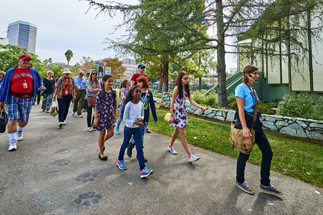 Museum Educator leading visitors along a path with big cat paw prints