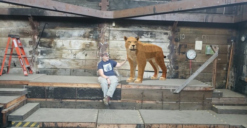 Fossil Preparator next to digital saber-toothed cat in tar pit