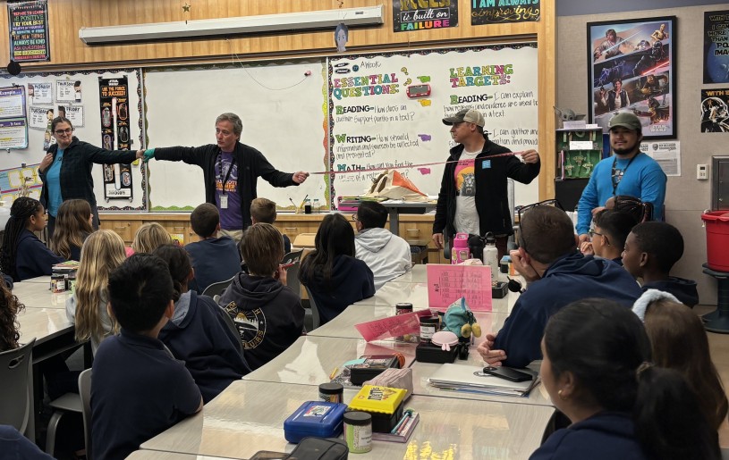 La Brea Tar Pits Collections Manager Greg Davies demonstrates the gigantic wingspan of the teratorn to students in a classroom.