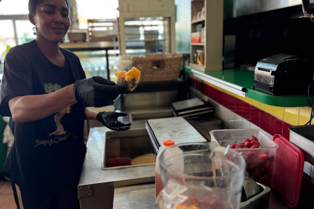 Mia Keeling carefully selecting and adding fresh, vibrant ingredients into a blender at Simply Wholesome.